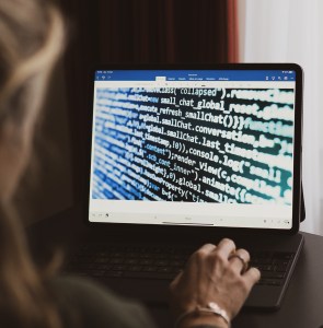 femme devant un écran d'iPad rempli de lignes de code