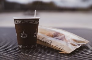 café à l'emporter fumant avec croissant dans emballage papier