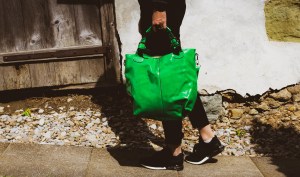 Femme vêtue de noir portant un sac à main en vinyle vert
