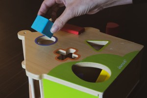 main d'adulte essayant de placer un bloc sur un jeu de formes pour enfant